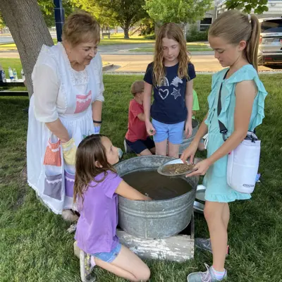 youth learn about pioneer washing at tub in the yard with whitaker expert helping 